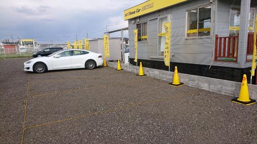 a white car parked next to a building with yellow cones at ゲストハウス岐阜羽島心音 Guest House Gifuhashima COCONE in Hashima