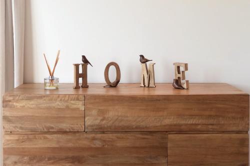 a wooden dresser with wooden letters on top of it at Deluxe Coastal Home & Award-winning Golf in Whangaparaoa