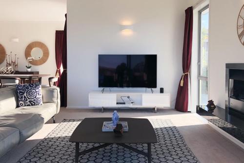 a living room with a couch and a tv at Deluxe Coastal Home & Award-winning Golf in Whangaparaoa