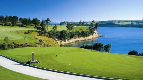 a golf course next to the water with a road at Deluxe Coastal Home & Award-winning Golf in Whangaparaoa