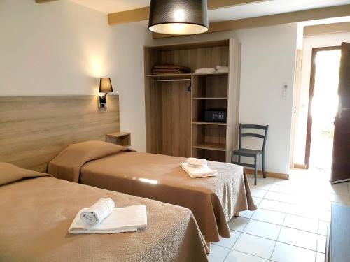 a room with two beds and a table and a chair at Hotel Olmuccio in Sainte-Lucie de Porto-Vecchio