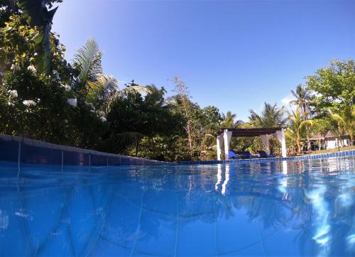a large swimming pool with a wooden pergola at Casa Amihan in Anda