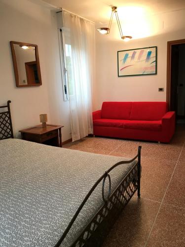 a bedroom with a red couch and a red bed at Pensione Imperia in Lignano Sabbiadoro