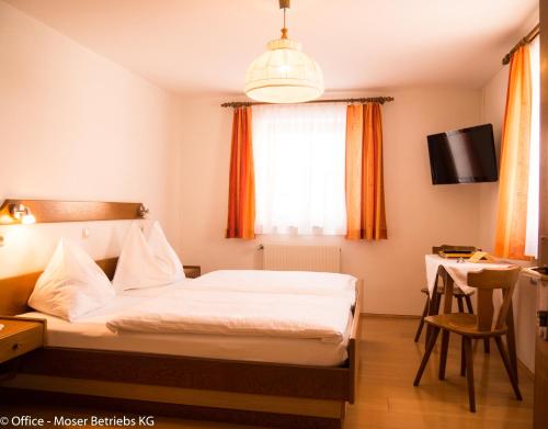 a bedroom with a bed and a desk and a tv at Alpengasthof Moser in Karchau