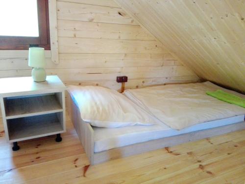 a bed in a room with a wooden wall at Gościniec Echo in Piecki