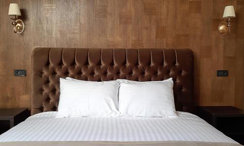 a bed with a brown headboard and white pillows at Shato Luxe in Odesa