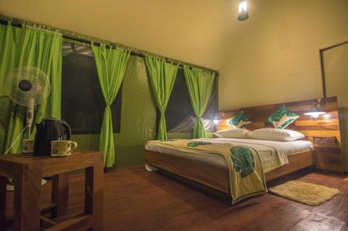 a bedroom with a large bed with green curtains at 360 Rainforest in Deniyaya