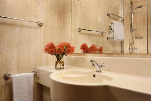 a bathroom with a sink and a vase of red flowers at UNAHOTELS Scandinavia Milano in Milan