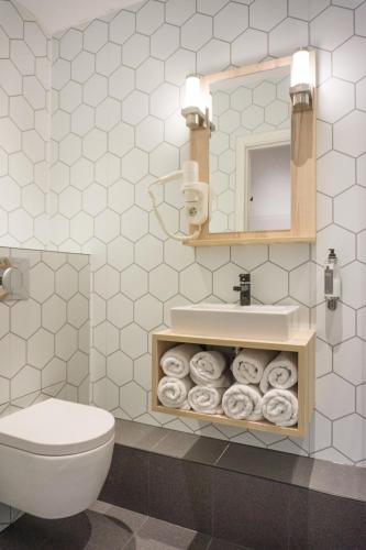 a bathroom with a toilet and a mirror and towels at Hotel Nes Amsterdam in Amsterdam