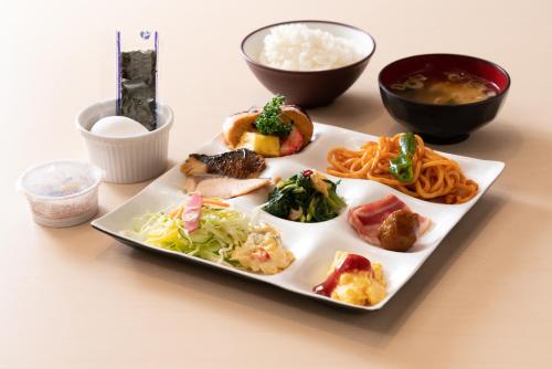 a plate with different types of food on a table at Murayama Nishiguchi Hotel in Murayama