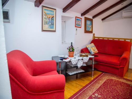 una sala de estar con 2 sillas rojas y una mesa. en Old town apartmant en Dubrovnik