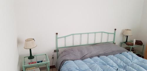 łóżko z niebieską kołdrą w sypialni w obiekcie Villa da Titti e Carlo w mieście Sarroch