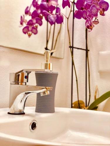 a bathroom sink with a faucet and purple flowers at Villa da Bisa with heated swiming pool in Arco da Calheta