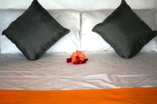 a white bed with two pillows and a red flower on it at Kilwa Beach Lodge in Kilwa Masoko