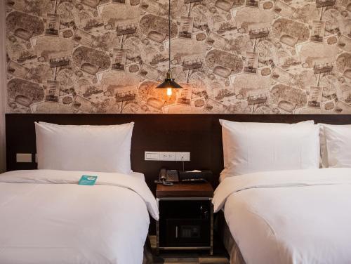 two beds in a hotel room with white sheets at Khan Hotel in Kaohsiung