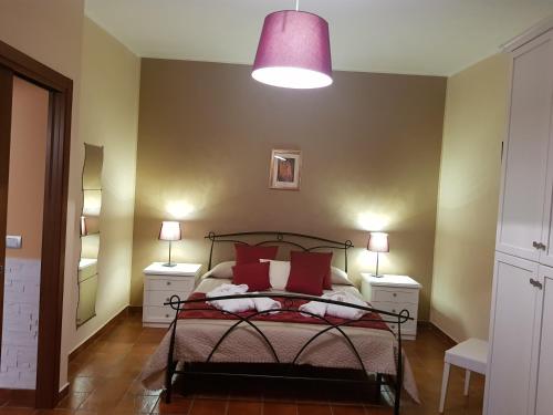a bedroom with a bed with red pillows and a pink lamp at Il Giardino di Tolù Siracusa in Città Giardino