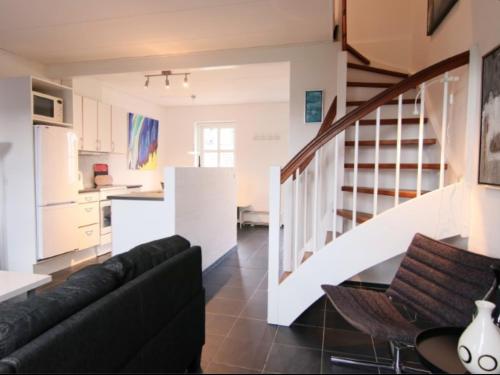 a living room with a black couch and a kitchen at Tversted Strandpark in Bindslev