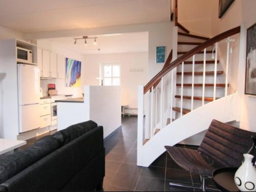 ein Wohnzimmer mit einem schwarzen Sofa und einer Küche in der Unterkunft Tversted Strandpark in Bindslev