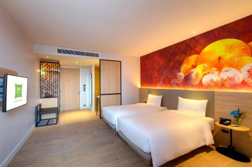 a hotel room with two beds and a painting on the wall at ibis Styles Bangkok Ratchada in Bangkok