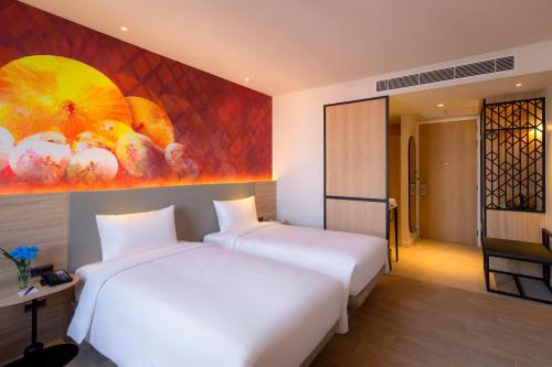 two beds in a room with a painting on the wall at ibis Styles Bangkok Ratchada in Bangkok