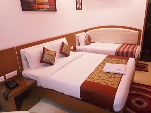 a hotel room with two beds and a telephone at Hotel Suktara International in Siliguri