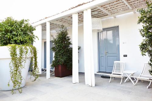 a white house with white columns and a blue door at La Suite Boutique Hotel in Procida