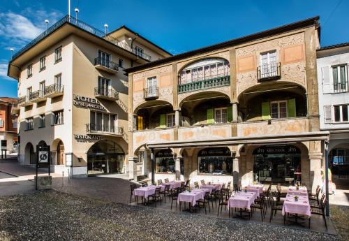 a building with pink tables and chairs in front of it at EasyRooms dell'Angelo in Locarno