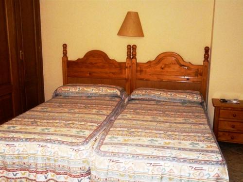 a bed with a wooden headboard in a bedroom at Hostal Rural Casa Castro in Alberuela de la Liena