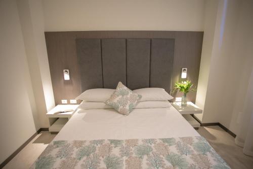 a bedroom with a large white bed with two tables at Mosella Suite Hotel in Sottomarina