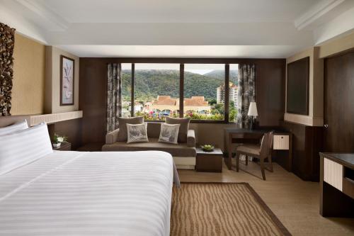 a hotel room with a large bed and a desk at Shangri-La Golden Sands, Penang in Batu Ferringhi