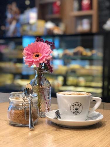 a cup of coffee and a vase with flowers on a table at Bayer's Boardinghouse und Hotel in Munich