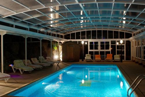 a large swimming pool with a ceiling and chairs at Logis Cosy - Hôtel Le Moulin Neuf - Chantonnay in Chantonnay