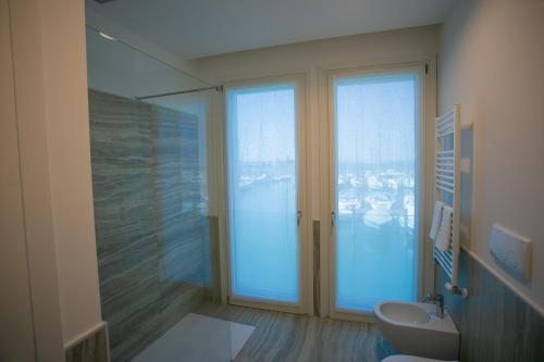 a bathroom with a large glass window and a toilet at Mosella Suite Hotel in Sottomarina