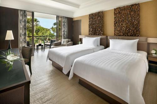 two beds in a hotel room with a balcony at Shangri-La Golden Sands, Penang in Batu Ferringhi