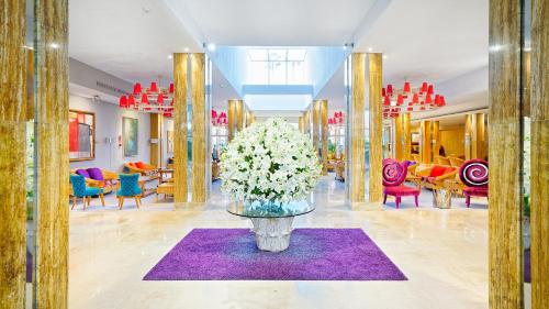 a lobby with a vase of flowers on a purple rug at Bull Reina Isabel & SPA in Las Palmas de Gran Canaria