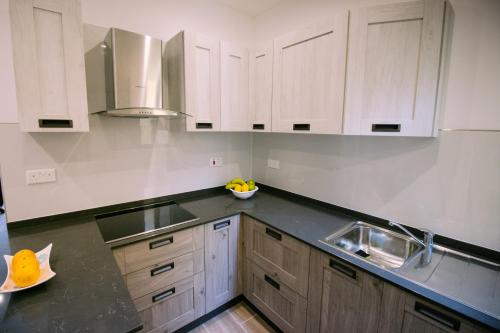 uma cozinha com armários brancos e um lavatório em Seafront Apartment No 10 Marsalforn em Marsalforn