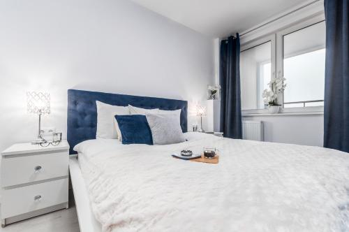 - une chambre avec un grand lit blanc et une tête de lit bleue dans l'établissement Apartments Golden Warsaw by Renters, à Varsovie
