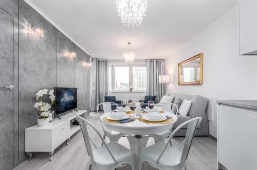 a dining room and living room with a white table and chairs at Apartments Golden Warsaw by Noclegi Renters in Warsaw