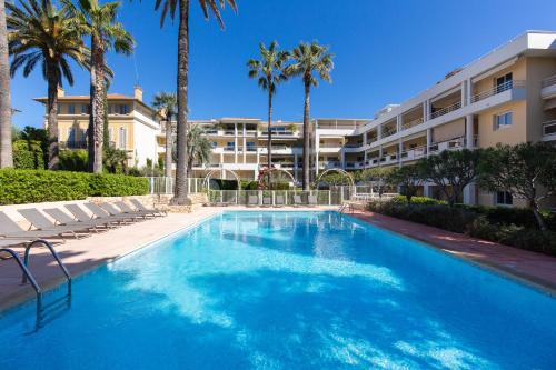 une piscine devant un immeuble avec des palmiers dans l'établissement Villa AD’ALTA, à Cannes