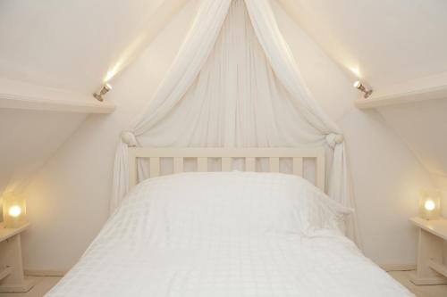 Welsh Gatehouse في Mathern: سرير أبيض مع ستارة في غرفة النوم
