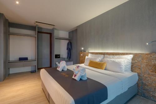 a bedroom with a large bed with two dolls on it at DARA Hotel - SHA Plus in Phuket Town