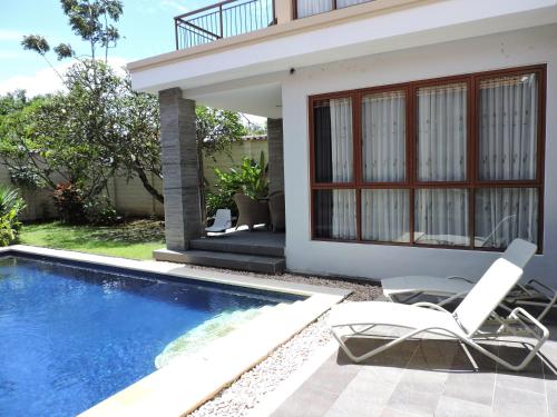 a house with a swimming pool and two chairs next to it at Accessible Penyaringan in Sanur