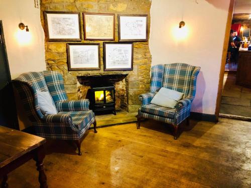 a living room with two chairs and a fireplace at The Hollybush Inn and B&B in Priors Marston