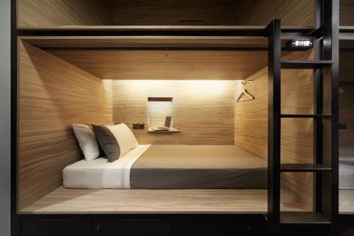 a bed in a room with a wooden wall at The Pod at Beach Road Boutique Capsule Hotel in Singapore