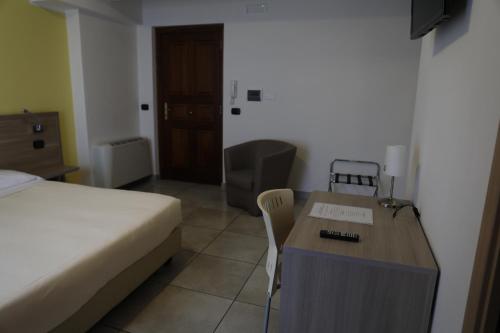 Cette chambre comprend un lit, un bureau, un lit et une table. dans l'établissement Garnì House Majorana, à Rende
