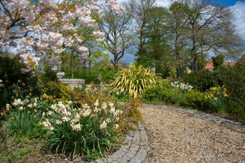 a garden with flowers and a stone path at The Coach House Suffolk in Lowestoft