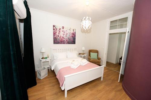 a white bedroom with a bed and a chandelier at Old Fortress Luxury Suite in Corfu Town