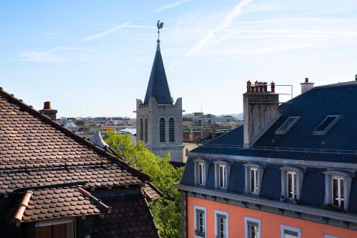 a steeple of a church in a city with roofs at Hotel D Geneva in Geneva