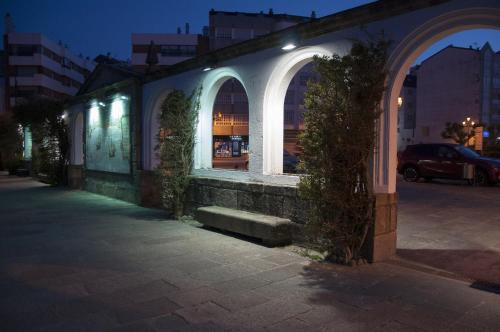 a building with arched windows on a street at night at Hotel Tres Carabelas in Baiona
