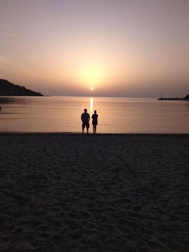 two people standing on the beach watching the sunset at VILA INSPIRATION - ON KINI BEACH in Kinion